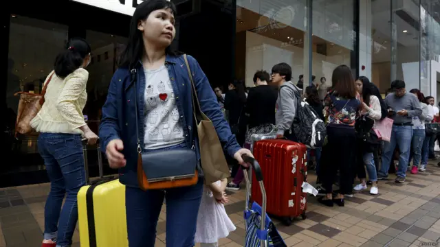 香港尖沙咀廣東道上拖著行李箱或購物車的中國大陸遊客(19/3/2015)