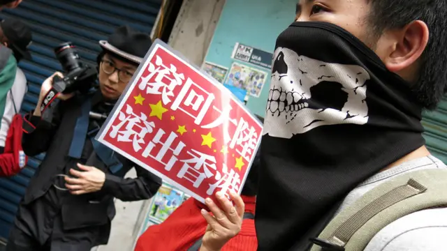 香港元朗反水客示威一名參加者舉起「滾回大陸,滾出香港」標語牌(BBC中文網圖片1/3/2015)