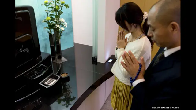 Люди молятся у могилы умершего родственника