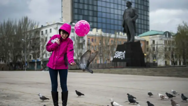 Дівчина годує голубів на площі Леніна у Донецьку 