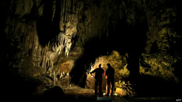 Stalakmit dan stalaktit berkilauan dalam kegelapan.