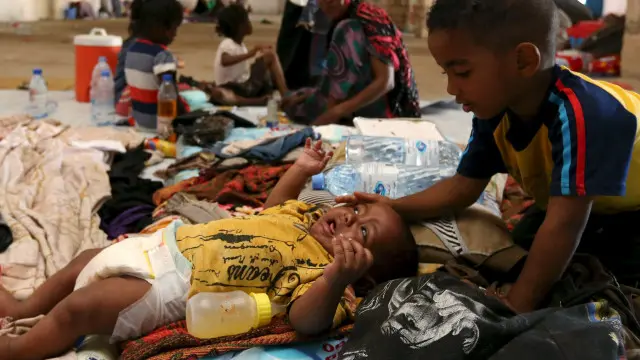 طفل يداعب شقيقه بأحد الملاجئ التي نزح إليها آلاف اليمنيين بسبب العنف في بلادهم.