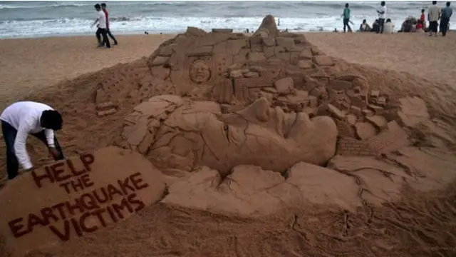 Hindistan'da bir sanatçı da deprem kurbanlarının anısına kumdan bir heykel yaptı. Heykelin üzerinde "Deprem kurbanlarına yardım edin" yazıyor.