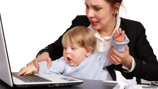 Una madre luchando con su pequeño para usar una laptop
