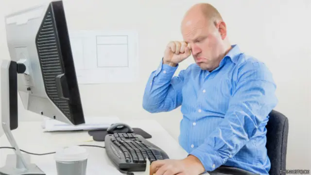 Hombre que se rasca los ojos frente a la computadora