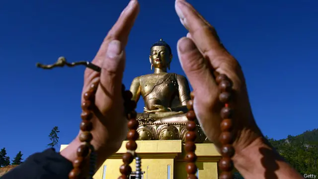Статуя Будды и ладони молящегося