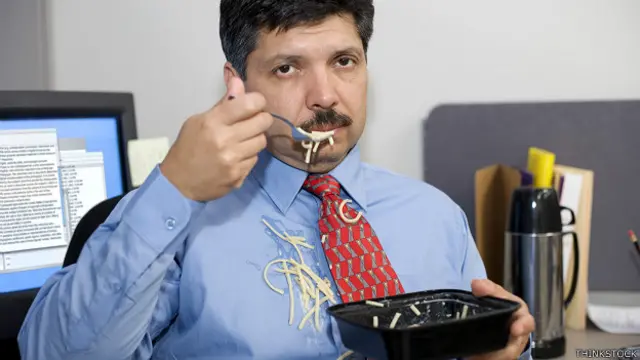 Un ejecutivo comiendo malamente en el escritorio