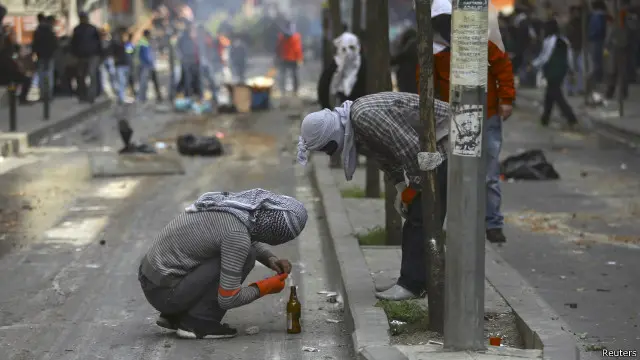 متظاهران يعدان قنبلة مولوتوف خلال اشتباكات مع الشرطة.