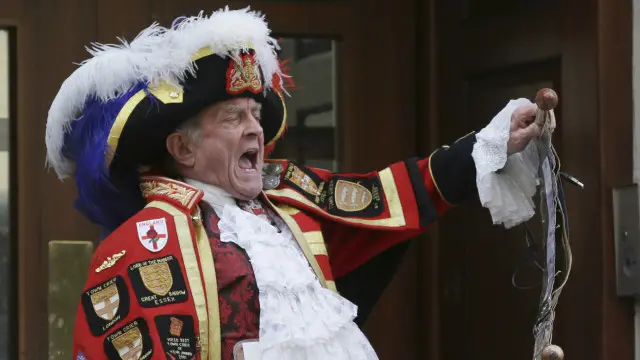 一名男子穿着传统服装，在医院门口大声宣布王室小公主诞生。