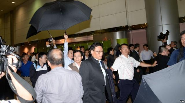 警方維安人員在桃園機場撐傘阻止台聯示威者向朱立倫扔雜物（台灣中央社圖片5/5/2015）