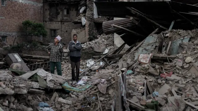 رہائشی زلزے میں تباہ ہونے والے اپنے مکانات کو حسرت سے دیکھ رہے ہیں۔ اس زلزلے میں سات ہزار کے قریب ہلاکتیں ہوئی تھیں۔