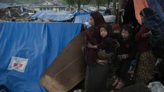 نیپال میں برپاک گاؤں میں تباہ ہونے والے مکانات کے قریب متاثرین کے لیے لگائے گئے خیموں سے چند خواتین اپنے مکانات کو دیکھ رہی ہیں۔