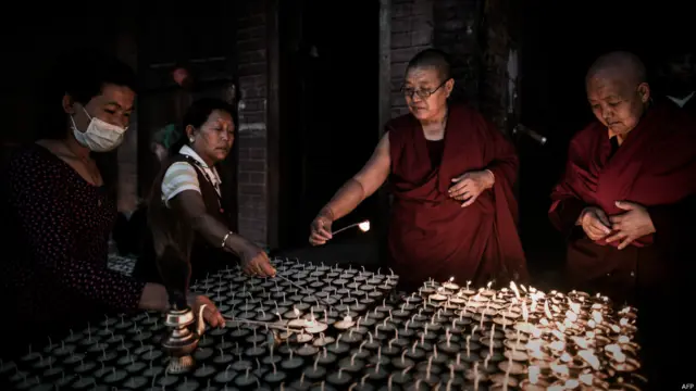 بدھ بھکشو کٹھمنڈو میں اپنے مذہبی دن بدھا پورنیما کے موقعے پر بدھاناتھ سٹوپا کے باہر چراغ روشن کر رہے ہیں۔