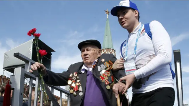 دوسری جنگ عظیم کے ایک فوجی کو سہارا دے کر ریڈ سکوائر کی جانب لایا جا رہا ہے۔ 