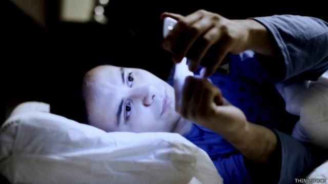 Una persona mirando su teléfono en la cama