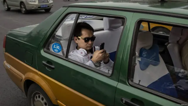 北京街头一辆出租车上乘客在使用智能手机（资料图片）