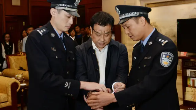 李华波（中）在北京首都机场接受逮捕后被锁上手铐（新华社图片9/5/2015）