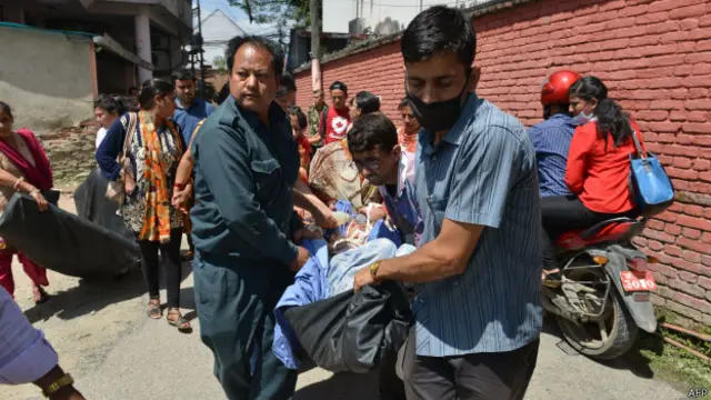 Para petugas rumah sakit memindahkan pasien ke luar gedung rumah sakit begitu gempa berlangsung.