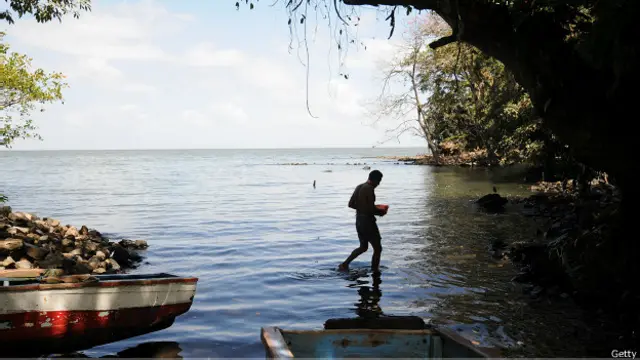 Una persona entre barcos pesqueros en una playa de Ometepe