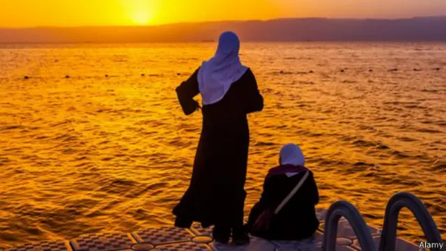 امرأتان من الأردن تشاهدان غروب الشمس في خليج العقبة على البحر الأحمر بالأردن.