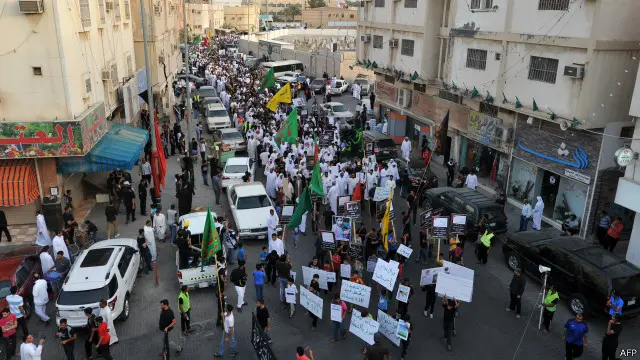 سعوديون يحملون لافتات خلال مسيرة في بلدة القديح بمحافظة القطيف تنديدا بالهجوم