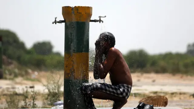 شدید گرمی سے بچنے کے لیے ایک مزدور پانی نلکے کے نیچے بیٹھ گیا۔ گذشتہ دو ماہ سے ملک کے کئی خطوں میں شدید گرمی کی لہر سے سینکڑوں افراد ہلاک ہو گئے ہیں۔ 