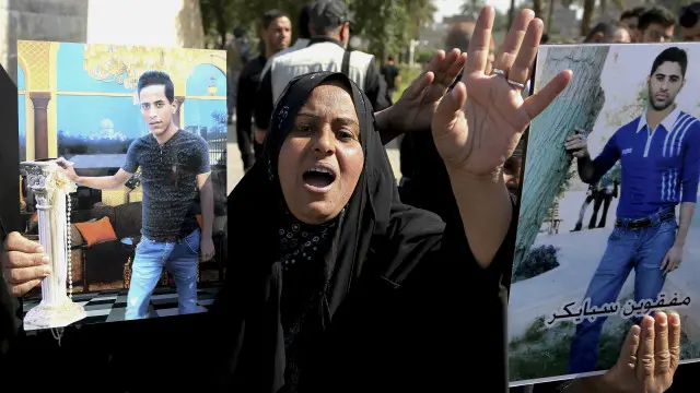 ایک عورت اپنے دو بچوں کی تصاویر کے ساتھ حکومت سے مطالبہ کر رہی ہے کہ کیمپ سپائیکر کے قتل کے ملزمان کو سزا دی جائے