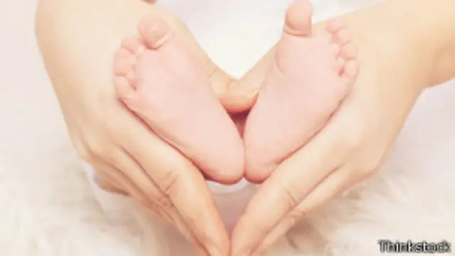 Pies de un bebé entre las manos de su madre
