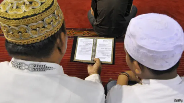 Dua orang warga Muslim tengah membawa kitab suci Al-Quran.
