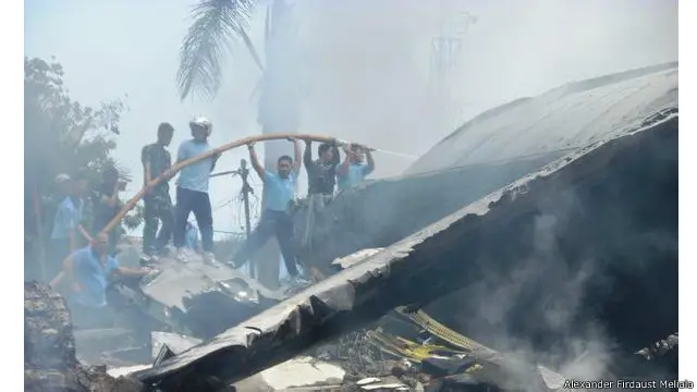 Petugas tampak berusaha memadamkan api sesaat setalah pesawat Hercules jatuh di Jl. Jamin Ginting Medan.