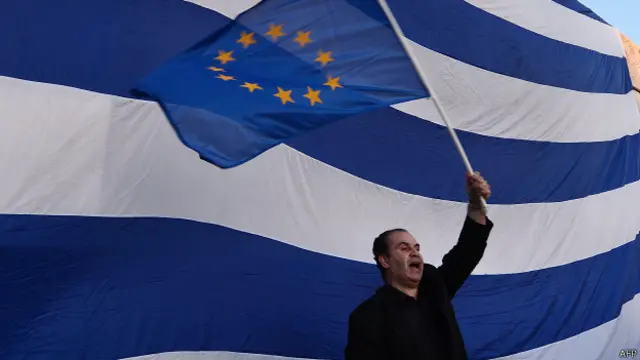 Мужчина с флагом Евросоюза на фоне греческого флага