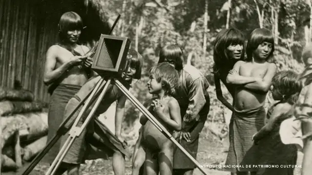 Indígenas alrededor de una cámara.