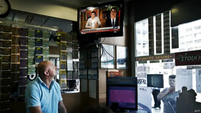 希腊一家彩票店老板收看电视上的齐普拉斯讲话