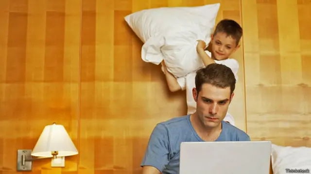 Сын замахивается подушкой на работающего отца