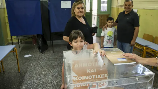 希腊雅典某投票站一名小女孩替祖母把公投选票投入票箱（5/7/2015）