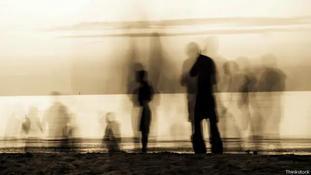 Размытые фигуры ходят по пляжу