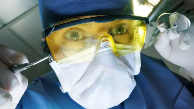 Un dentista que se aproxima con sus instrumentos