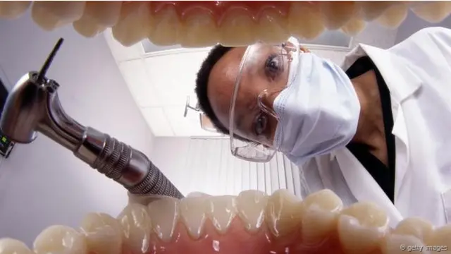 Un dentista que se acerca con instrumentos