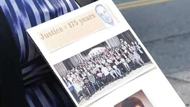 Una víctima sostiene un cartel con la foto del médico y sus víctimas. Piden 175 años de cárcel para él.