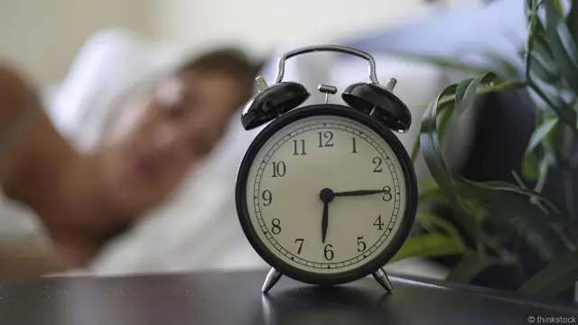 Будильник на фоне женщины в постели