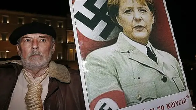 Un manifestante griego con una pancarta de Angela Merkel