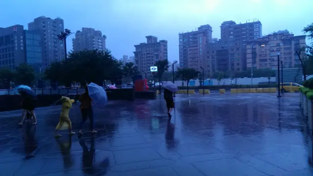 台北市的天空灰濛濛，整天下著雨，有時會颳起強風，讓撐傘的路人措手不及