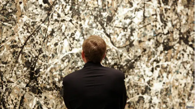 Una persona mirando un cuadro de Jackson Pollock