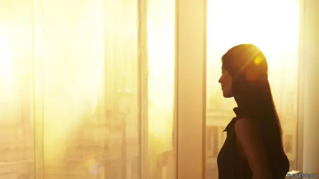 Una persona mira el amanecer en su ventana