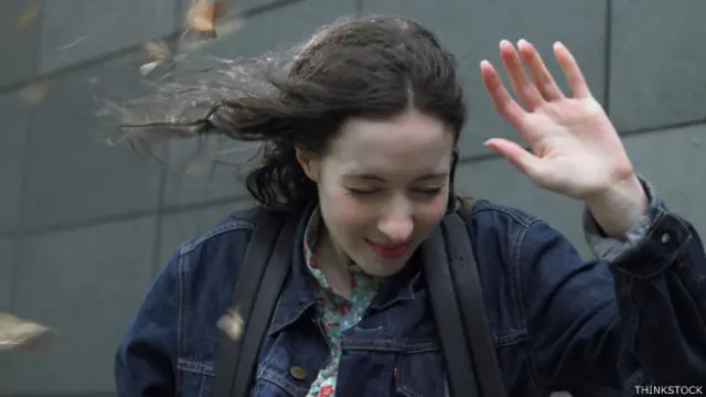 Mujer resiste el viento cerca de un edificio
