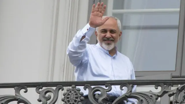 Menlu Iran Javad Zarif melambai kepada wartawan dari balkon hotel di Wina.