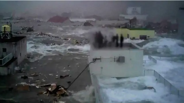 Caption: Foto yang diambil penduduk setempat memperlihatkan pegawai bank terjebak di atap saat permukaan air naik © Yoshinori Hara