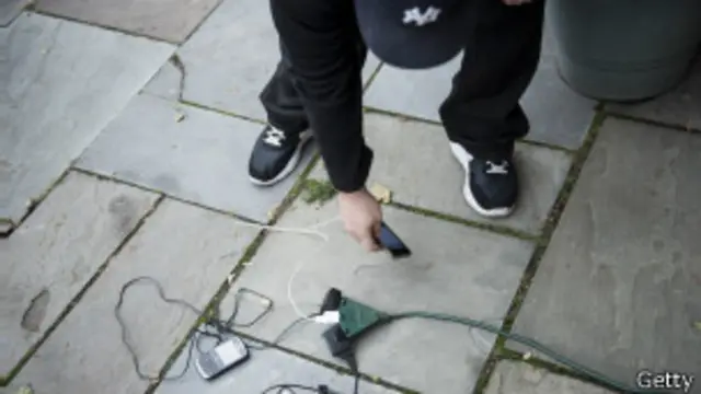 Persona recarga su celular en la calle