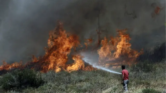 أحد المواطنين يحاول إطفاء ألسنة اللهب وإبقاءها بعيدا عن منزله.