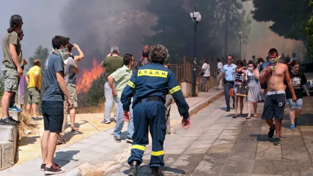 سكان منطقة كيريا، إحدى ضواحي أثينا يغادرون منازلهم بينما يحاول رجال الإطفاء التعامل مع ألسنة اللهب.